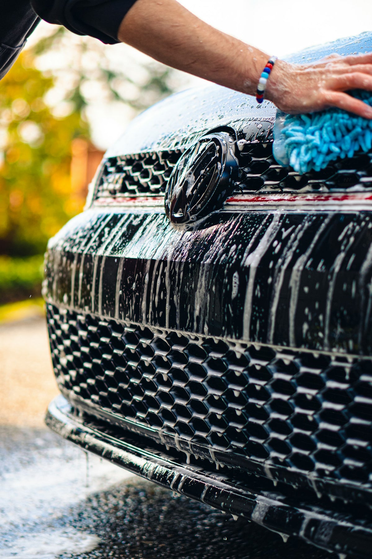 Cleaning a black car with a blue microfibre cloth, photographed by Jackson Eaves