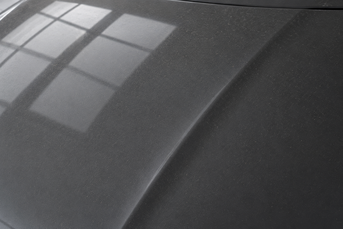 Illustration of a graphite car hood with a light dust film before cleaning